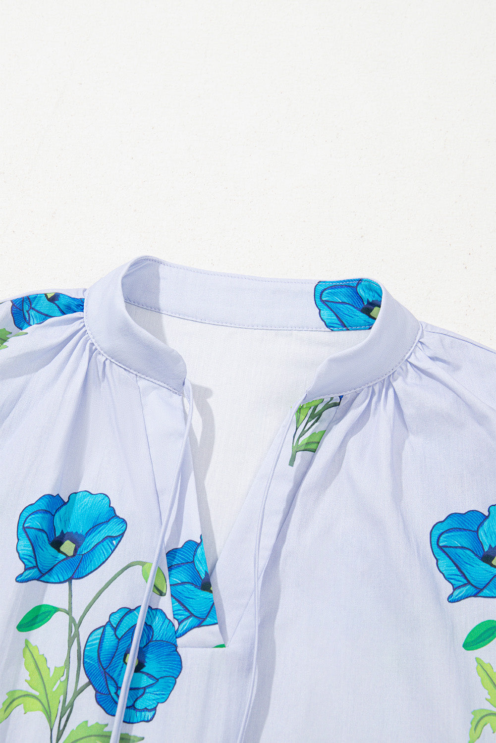 Chemisier bleu ciel à imprimé floral, col noué et manches courtes