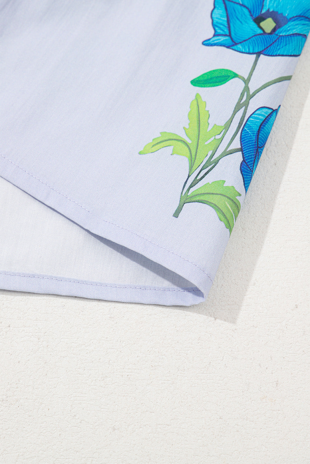 Chemisier bleu ciel à imprimé floral, col noué et manches courtes