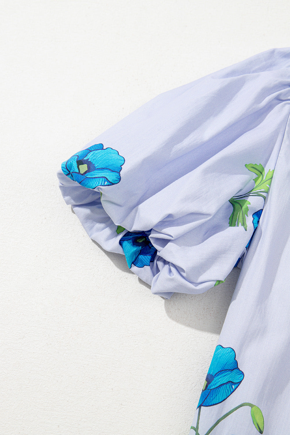 Chemisier bleu ciel à imprimé floral, col noué et manches courtes